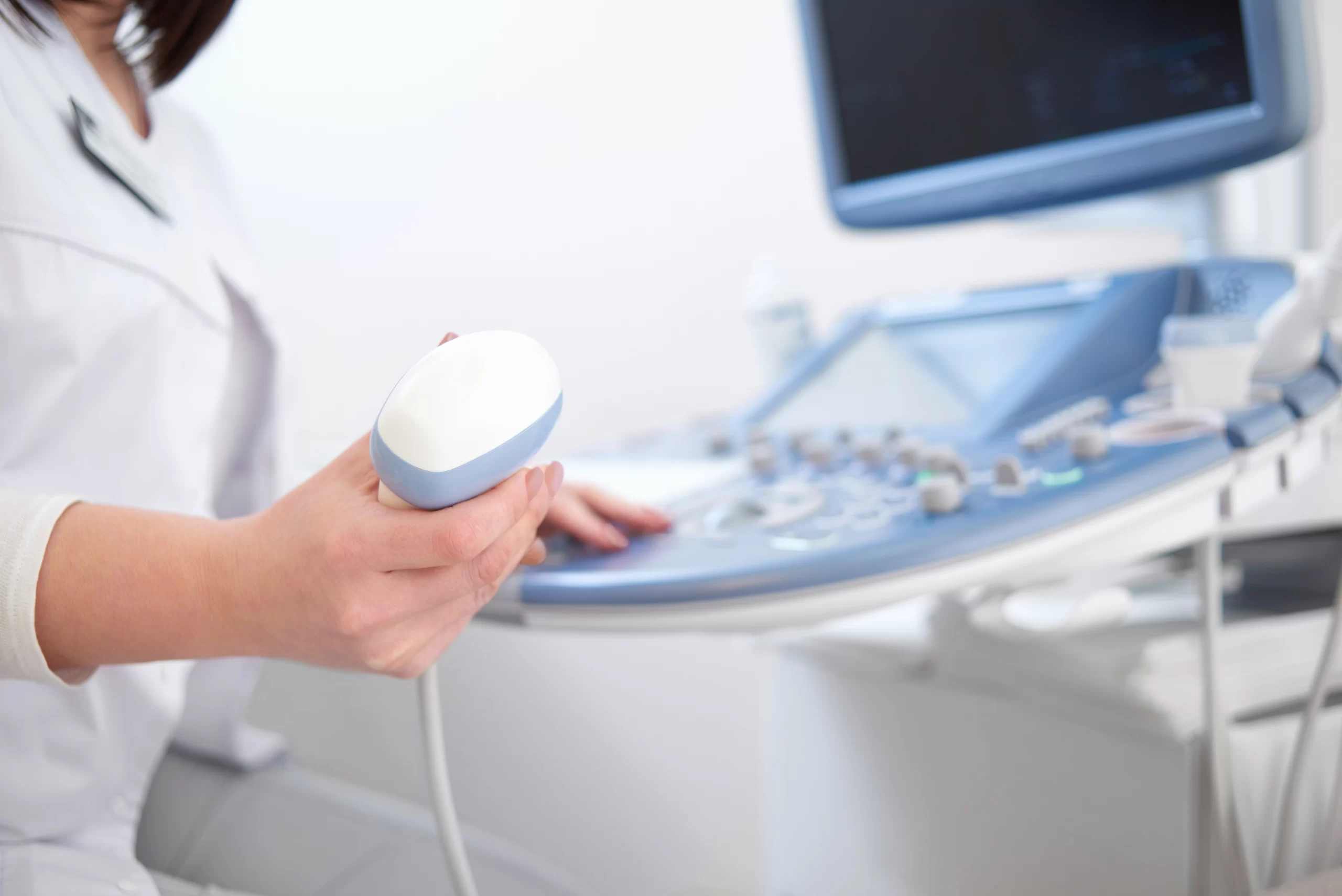 Sonografista profesional sosteniendo el transductor de un equipo de ultrasonido de alta resolución.